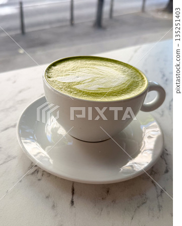 Matcha latte in white ceramic cup on saucer close-up. Japanese tea culture, healthy lifestyle and modern cafe trend. Matcha latte in white ceramic cup on saucer close-up. Japanese tea culture, healthy lifestyle and modern cafe trend. 135251403
