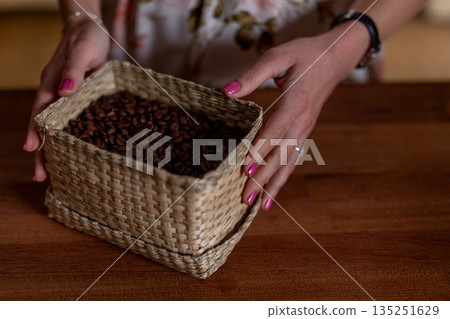 Artisanal arrangement of beans in woven basket on wooden surface, Carefully crafted display of beans inside handmade basket atop warm kitchen table with decorative rings Artisanal arrangement of beans in woven basket on wooden surface, Carefully crafted display of beans inside handmade basket atop warm kitchen table with decorative rings 135251629