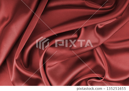 Crumpled, wrinkled red colored glossy silk satin texture. Shiny fabric cloth with wave folds Crumpled, wrinkled red colored glossy silk satin texture. Shiny fabric cloth with wave folds 135251655