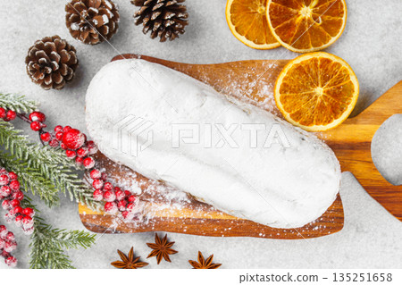Traditional Christmas Stollen, sweet fruit loaf with sugar icing on wooden board and festive decor Traditional Christmas Stollen, sweet fruit loaf with sugar icing on wooden board and festive decor 135251658