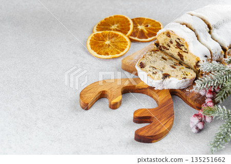 Traditional sliced Christmas stollen loaf with raisins and powdered sugar on wooden cutting board Traditional sliced Christmas stollen loaf with raisins and powdered sugar on wooden cutting board 135251662
