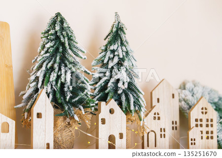 Minimal Christmas decor with wooden houses and snowy tabletop fir trees Minimal Christmas decor with wooden houses and snowy tabletop fir trees 135251670