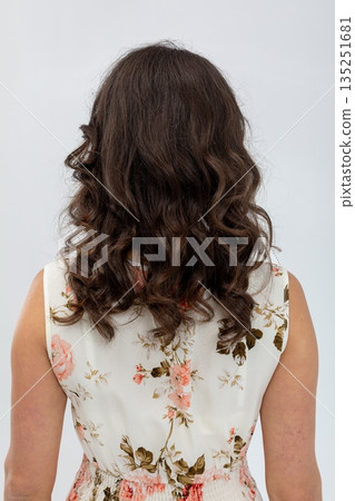 Studio shot of woman showcasing casual floral attire and relaxed demeanor, Portrait of female model with loose dark curls and timeless fashion style in bright studio setting 135251681