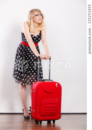 woman pulling heavy red travel bag woman pulling heavy red travel bag 135251935