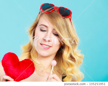 Woman holds red heart love symbol and lollipop candy 135251951