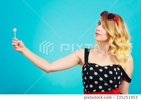 Cheerful girl holding little lollipop candy in hand 135251953