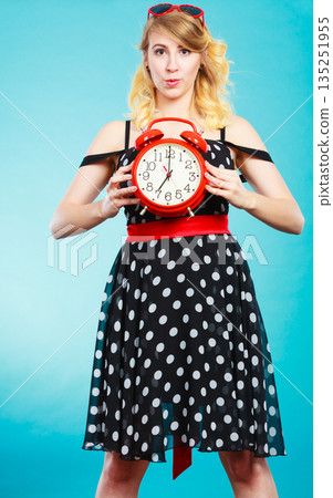 Blonde girl with alarm clock on blue. 135251955