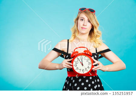 Blonde girl with alarm clock on blue. 135251957
