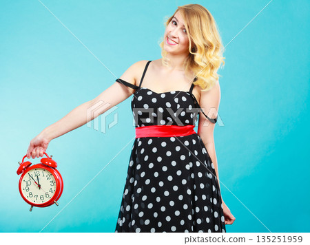 Smiling girl with alarm clock on blue. 135251959