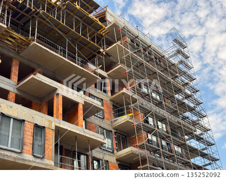 Building under construction with visible concrete floors and scaffolding. Urban development, civil engineering, and modern infrastructure progress. 135252092
