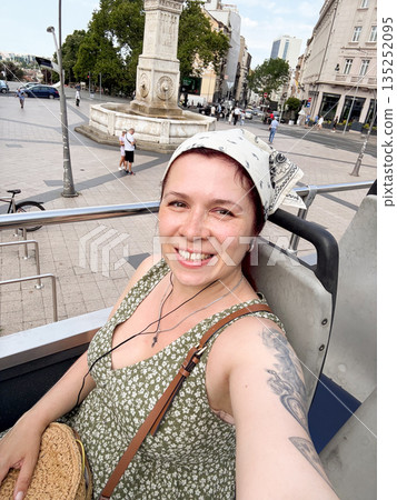 Woman on open top bus in city tour. Urban sightseeing, lifestyle travel and summer exploration. Woman on open top bus in city tour. Urban sightseeing, lifestyle travel and summer exploration. 135252095