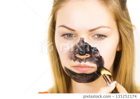 Girl being apply black mask to skin face Girl being apply black mask to skin face 135252174