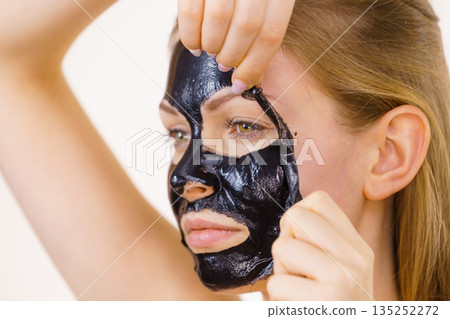 Girl removes black mask from face 135252272