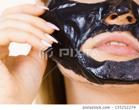 Girl with dried peel-off black mask on face 135252274