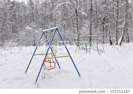 Hanging swing and staircase in a snowy forest park Hanging swing and staircase in a snowy forest park 135252297