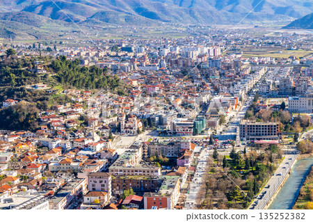 Daytime panoramic cityscape with dense residential neighborhoods, central streets, riverside park and urban sprawl across the valley with surrounding hills, Berat, Albania Daytime panoramic cityscape with dense residential neighborhoods, central streets, riverside park and urban sprawl across the valley with surrounding hills, Berat, Albania 135252382