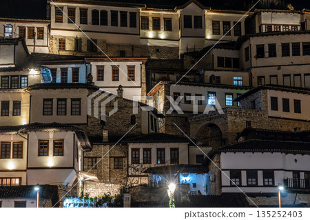 Night view of historic Albanian town with traditional Ottoman houses on a hillside with white stone architecture and illuminated windows, Berat, Albania Night view of historic Albanian town with traditional Ottoman houses on a hillside with white stone architecture and illuminated windows, Berat, Albania 135252403