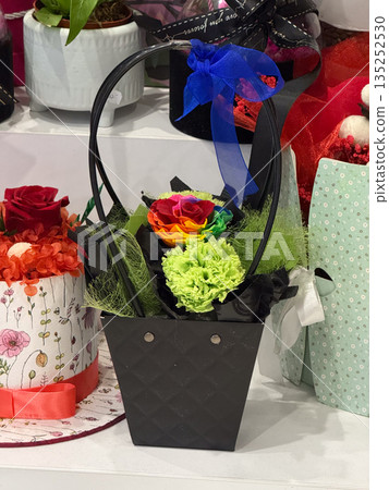 Black gift basket with rainbow rose and green carnation. Love, diversity, celebration, and joyful emotion through colorful floral arrangement 135252530