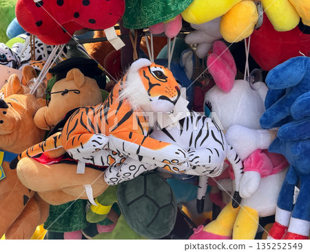 Tiger plush toys hanging together on a crowded street stall. Wild animal theme, soft fabric texture, and playful retail display 135252549
