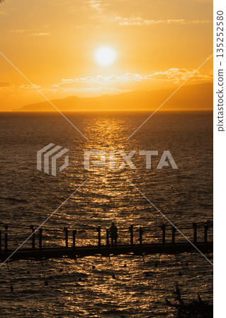 從城崎海岸的門脅吊橋上看到的日出，以及清晨的陽光反射在海面上的景象（伊豆） 135252580