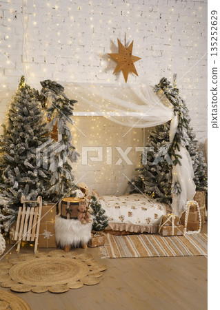 Winter holiday home decor with snowy Christmas trees, bed and warm fairy lights 135252629