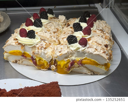 Meringue cake with cream and tropical fruit filling on display. Decadence, celebration, and handcrafted pastry culture through layered dessert composition 135252651