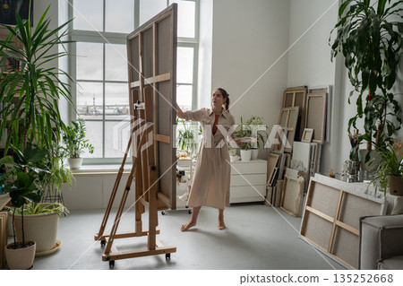 Woman artist in loft studio enjoying painting picture and releasing stress with art therapy class. Woman artist in loft studio enjoying painting picture and releasing stress with art therapy class. 135252668