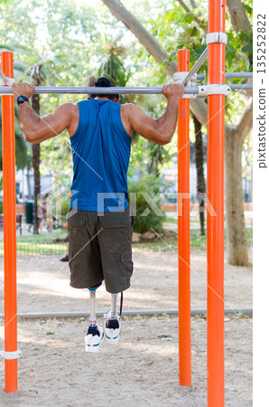 Unrecognizable Disabled athlete training pull ups in calisthenics park Unrecognizable Disabled athlete training pull ups in calisthenics park 135252822