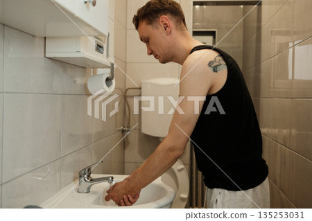 A man washes his hands in a small bathroom sink. The concept highlights hygiene and daily routine A man washes his hands in a small bathroom sink. The concept highlights hygiene and daily routine 135253031