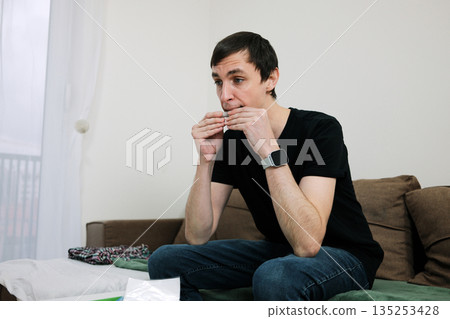 A man rolls a cigarette with both hands while sitting. The image reflects a habitual gesture and the concept of private routine 135253428