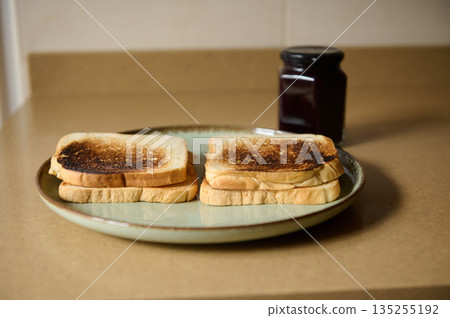 Two Toasted Bread Slices on a Plate with Jam Jar in Kitchen Two Toasted Bread Slices on a Plate with Jam Jar in Kitchen 135255192