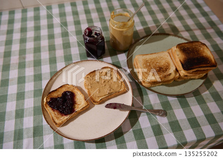 Family Breakfast Spread With Toast, Jam, And Peanut Butter On Checkered Tablecloth 135255202