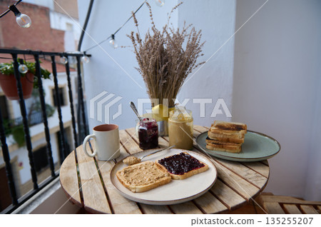 Cozy Balcony Breakfast With Toast, Jam, Peanut Butter, And Morning Light 135255207
