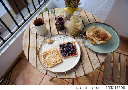 Cozy Balcony Breakfast With Toasts, Jam, Peanut Butter, Coffee, and Fresh Spreads Cozy Balcony Breakfast With Toasts, Jam, Peanut Butter, Coffee, and Fresh Spreads 135255208