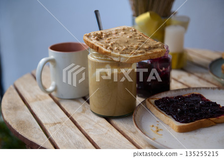 Peanut Butter Toast With Jam Jar, Coffee Mug, And Toast On Outdoor Wooden Table Peanut Butter Toast With Jam Jar, Coffee Mug, And Toast On Outdoor Wooden Table 135255215