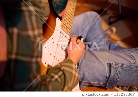 Casual Guitarist Playing Electric Guitar At Home In Plaid Shirt And Jeans 135255307