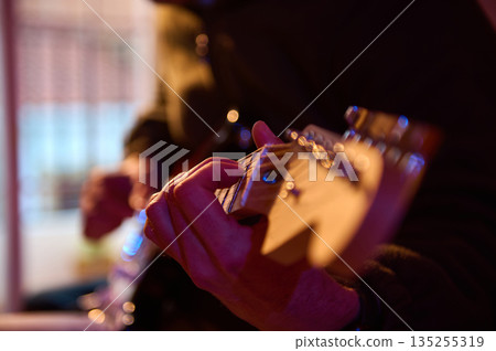 Close-Up Of A Guitarist's Hands Playing A Wooden Neck In Warm Studio Lighting 135255319