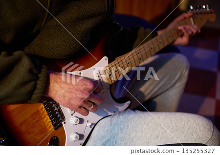 Close-Up Of Player Strumming An Electric Guitar In A Cozy Indoor Setting 135255327
