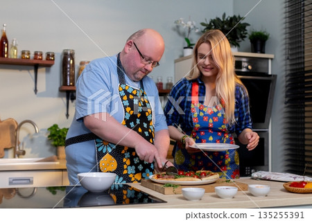 Preparing healthy meal, Coupled couple arranges fresh greens with cheerful guidance, Man and woman collaboratively prepare vibrant salad in contemporary kitchen setting 135255391
