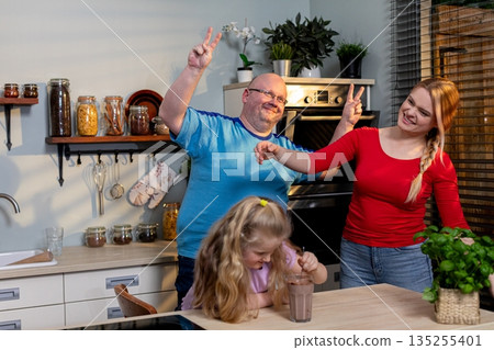 Family in cozy kitchen, Parents and child in warm kitchen, Happy family spending time in rustic kitchen setting, Casual family moment captured in charming home kitchen Family in cozy kitchen, Parents and child in warm kitchen, Happy family spending time in rustic kitchen setting, Casual family moment captured in charming home kitchen 135255401