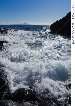 海浪拍打著礁石,遠處漂浮著一座小島。 海浪拍打著礁石,遠處漂浮著一座小島。 135255433