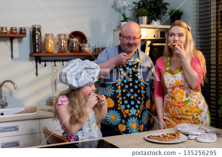 Father sampling bite while daughter chews and mother watches, informal judge scene with aprons and plates, tasting notes implied, playful critique and shared flavors 135256295