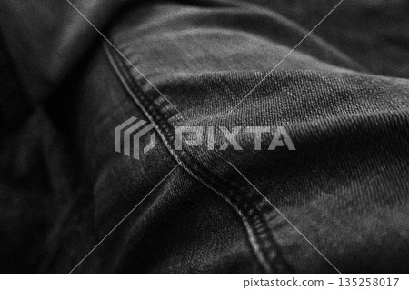 Detailed black denim texture with prominent seam and folded fabric, creating a versatile background for fashion or grunge designs Detailed black denim texture with prominent seam and folded fabric, creating a versatile background for fashion or grunge designs 135258017