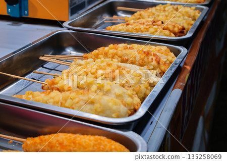 Delicious corn dogs displayed in metal trays under natural light, perfect for street food festivals and culinary events, showcasing savory snacks 135258069