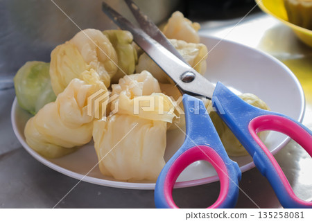Steamed dumplings and scissors on a plate, bathed in natural light, showcase culinary preparation, healthy eating, and delicious asian cuisine for a food blog Steamed dumplings and scissors on a plate, bathed in natural light, showcase culinary preparation, healthy eating, and delicious asian cuisine for a food blog 135258081