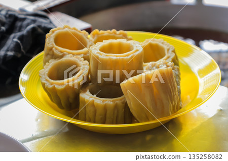 Bitter melon pieces served on a vibrant yellow plate under natural lighting, representing healthy eating and traditional cuisine 135258082