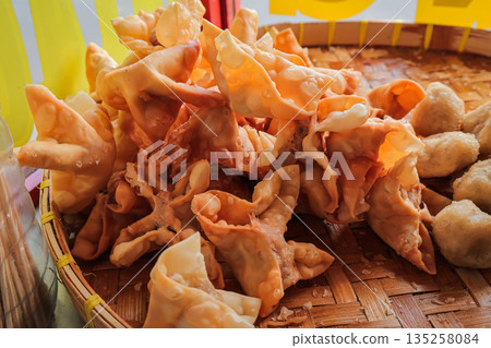 Crispy Pangsit Pile on Woven Tray with Natural Light highlighting golden texture, showcasing Indonesian culinary traditions and snack culture Crispy Pangsit Pile on Woven Tray with Natural Light highlighting golden texture, showcasing Indonesian culinary traditions and snack culture 135258084