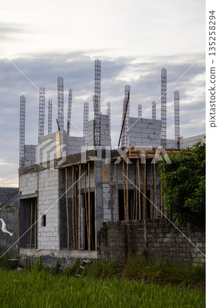 Unfinished House Construction with Steel Rebar and Concrete Blocks under Natural Light, showcasing ongoing residential development and copy space Unfinished House Construction with Steel Rebar and Concrete Blocks under Natural Light, showcasing ongoing residential development and copy space 135258294