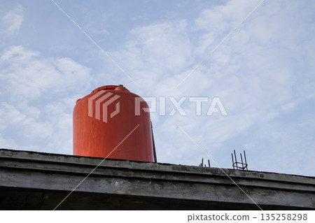 Orange Water Tank on Roof with Cloudy Sky in Background for Water Storage and Supply System under Natural Light Orange Water Tank on Roof with Cloudy Sky in Background for Water Storage and Supply System under Natural Light 135258298