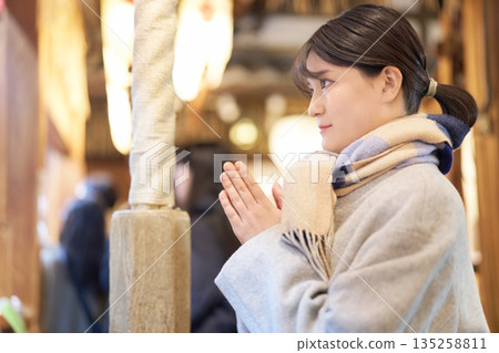 A woman wearing a scarf makes a serious wish at her first shrine visit of the year 135258811